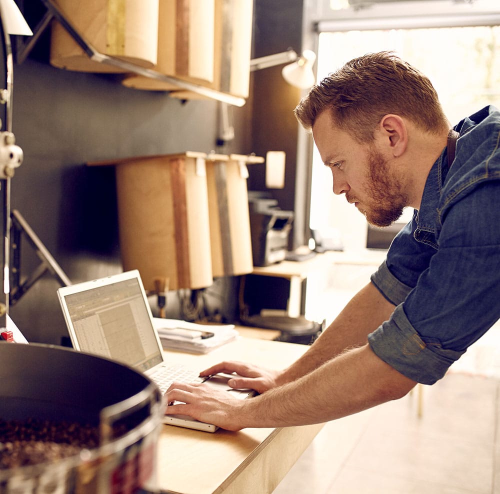Business owner of a coffee roastery checking his laptop
