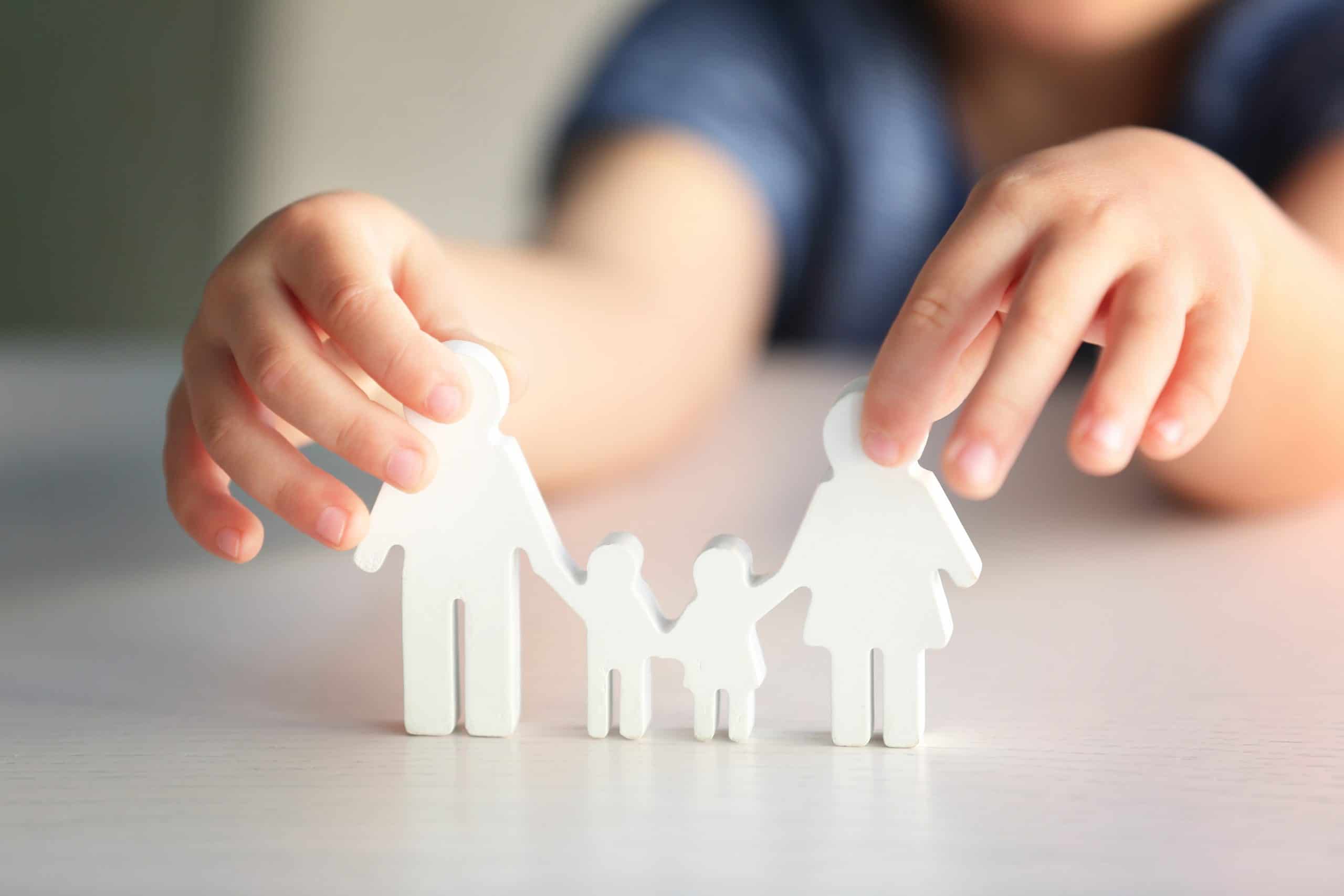 Child holding figure in shape of happy family, closeup