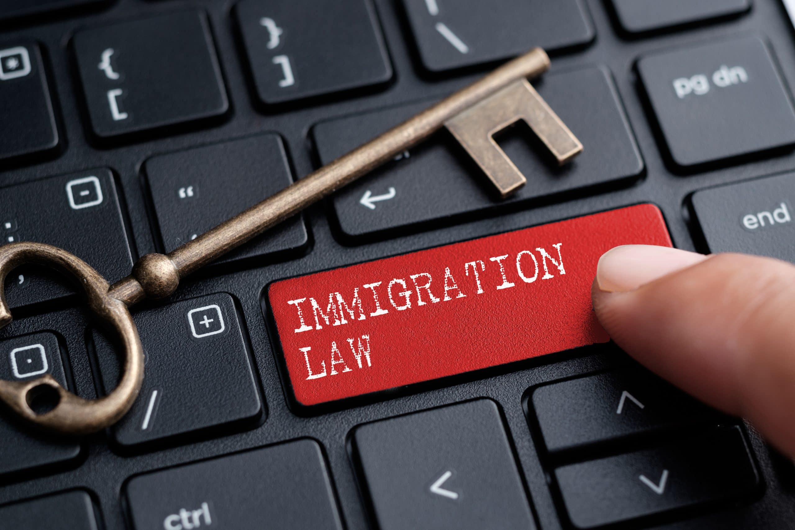 Closed up finger on keyboard with word IMMIGRATION LAW