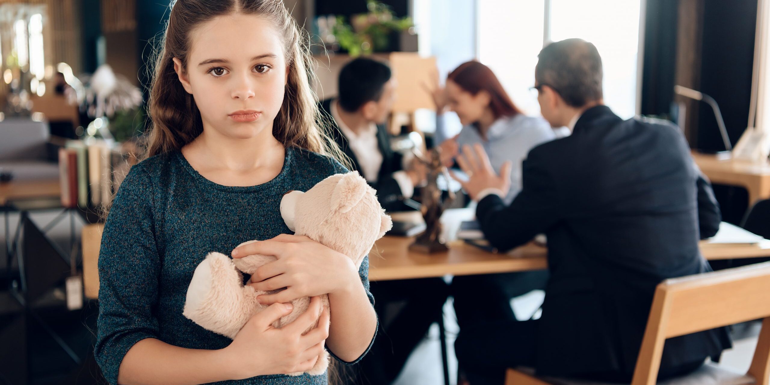 Little girl is hugging teddy bear at office of family lawyer